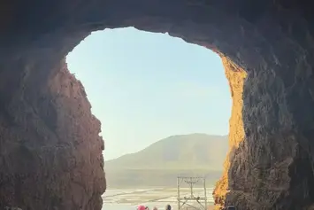 Turistas a atravessar um túnel rochoso em direção às Salinas de Pedra de Lume