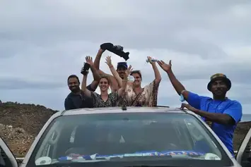 Grupo de amigos a celebrar em cima de um automóvel alugado durante um passeio